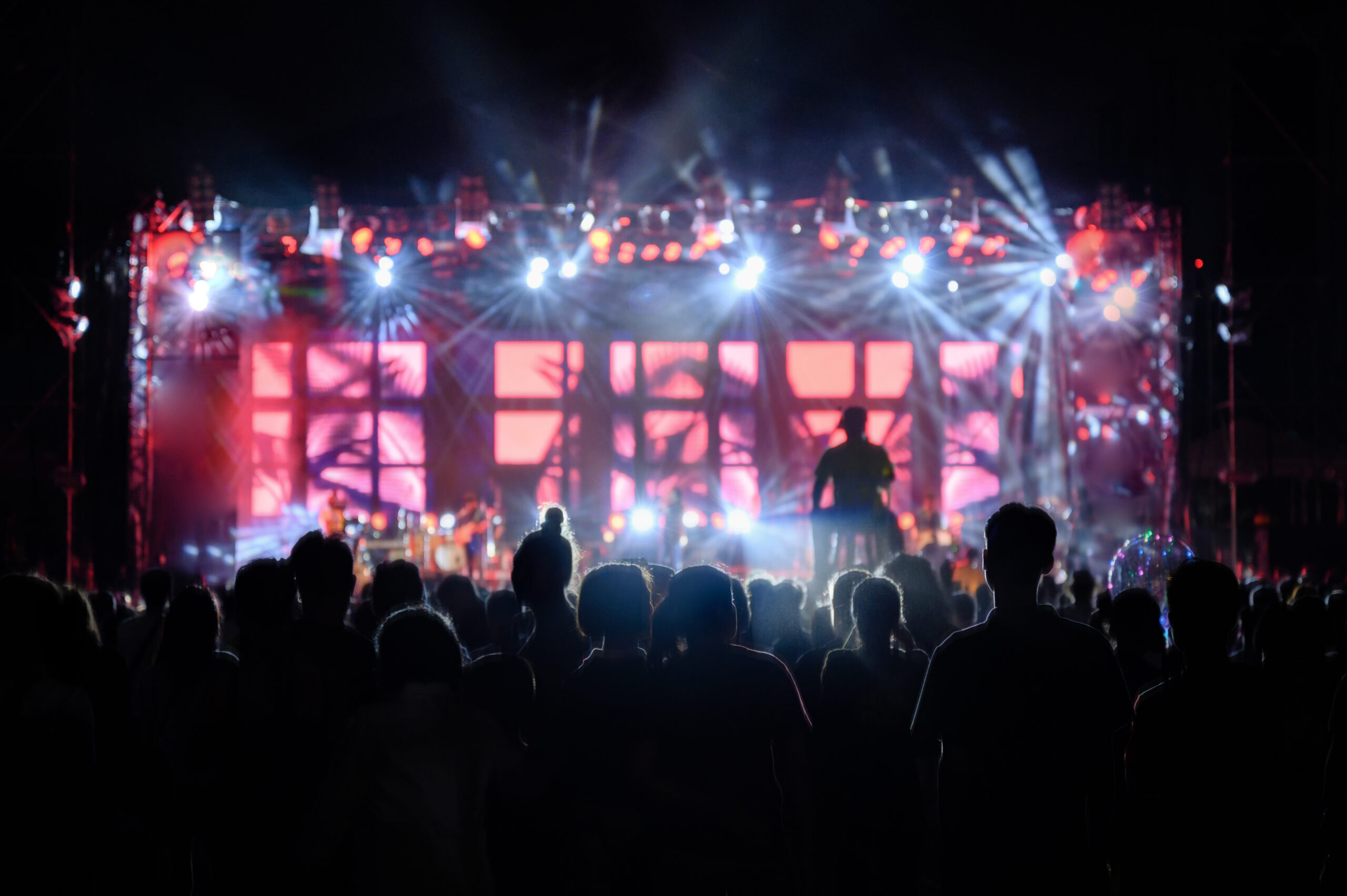 Silhouette youth audience are watching the night concert of stage light